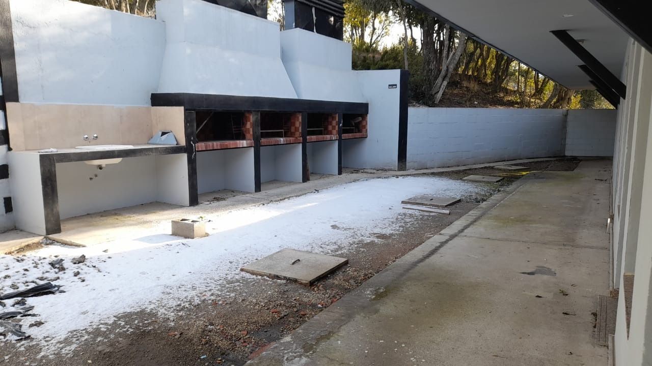 Outdoor grilling area with multiple charcoal grills, white walls, and a concrete path.