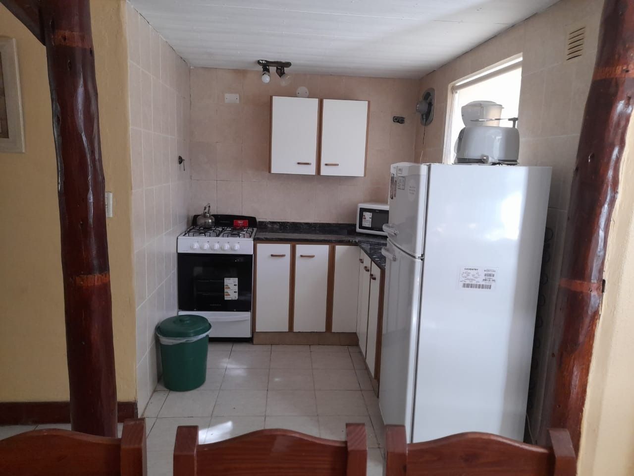 Small kitchen with white cabinets, appliances, and a green trash can.
