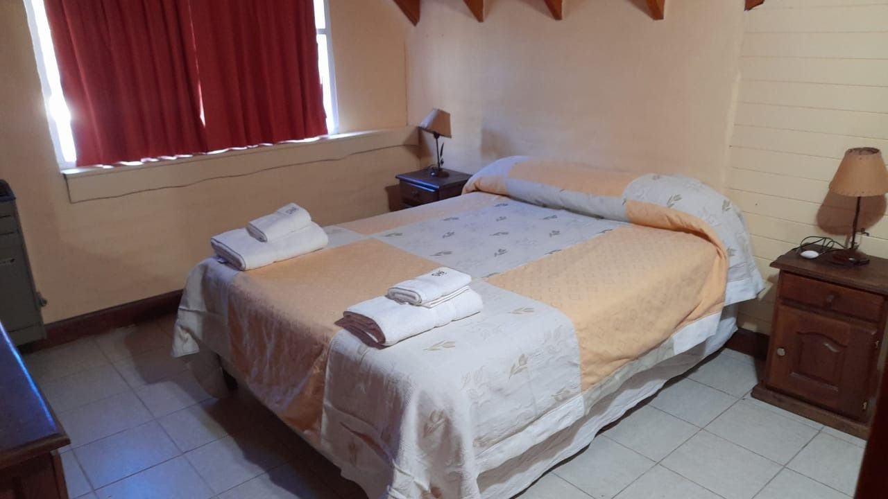 Bedroom with a double bed, two bedside tables with lamps, and a window with red curtains.