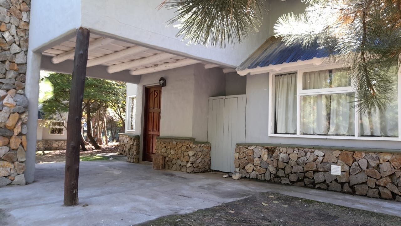 Exterior of a gray house with stone accents, a covered entrance, and a window with curtains.
