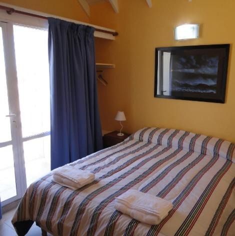 Bedroom with a striped bed, blue curtains, yellow walls, and a framed picture.
