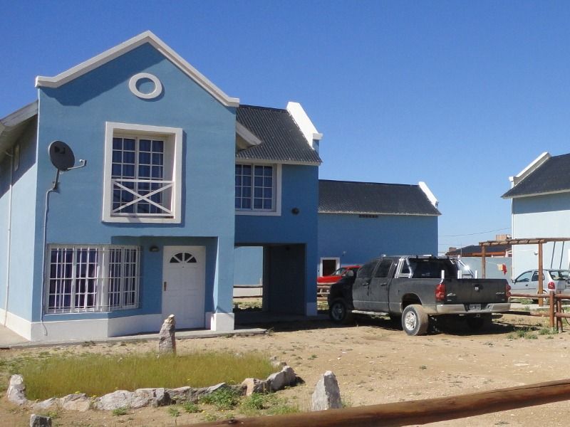 Blue two-story house with a white door and windows; a black pickup truck is parked outside.