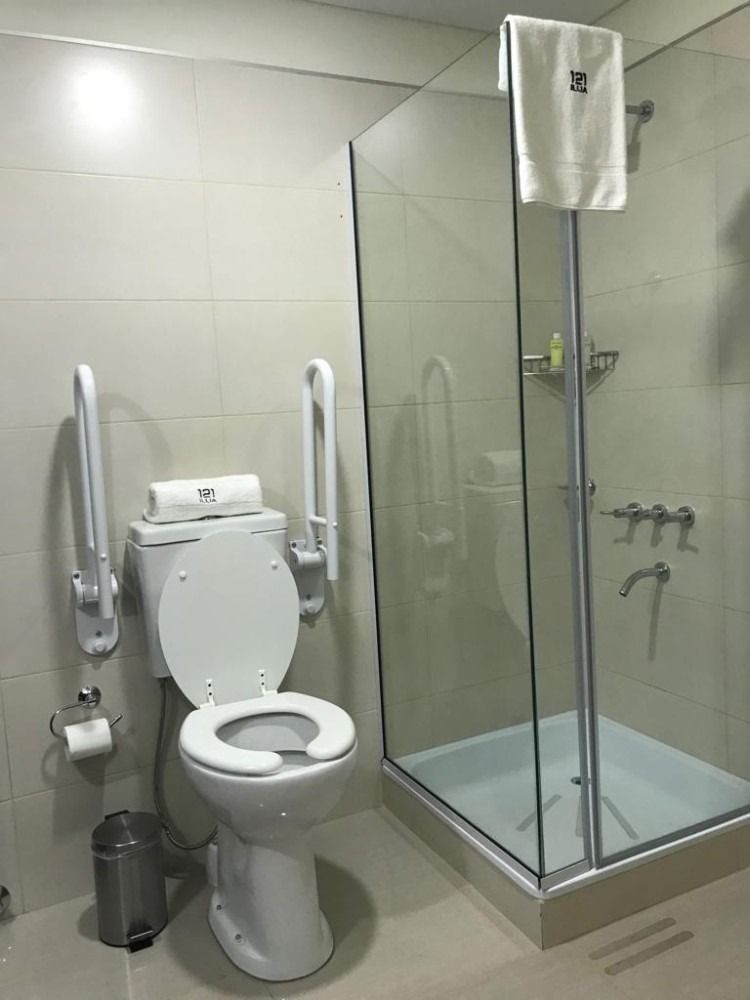 Bathroom with toilet and shower, featuring grab bars, and wheelchair-accessible features.