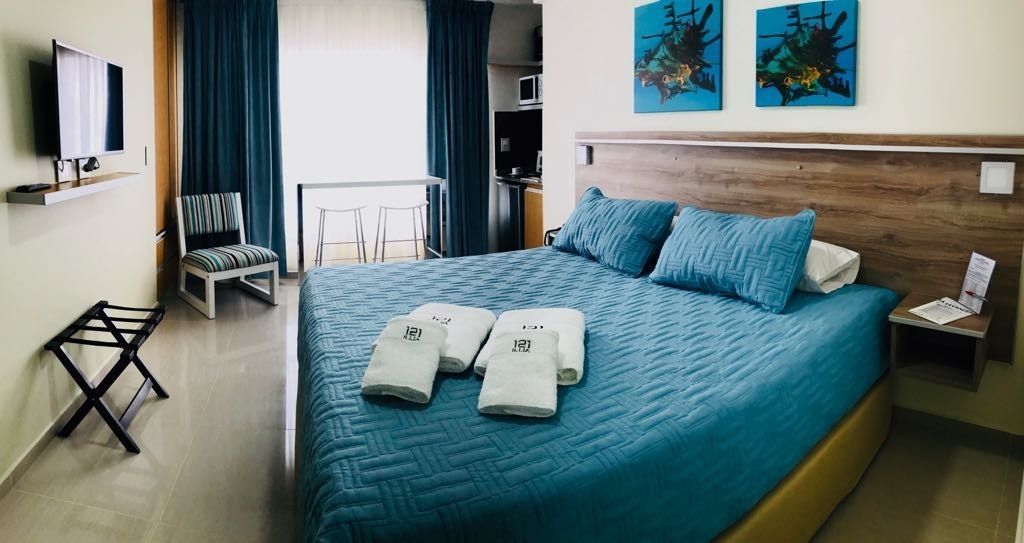 Hotel room with a large bed, blue bedding, and two framed ocean-themed art pieces above the headboard.