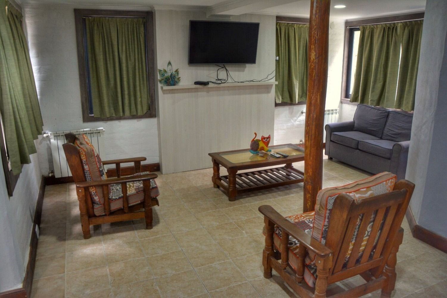 Living room with wooden furniture, TV, and green curtains.