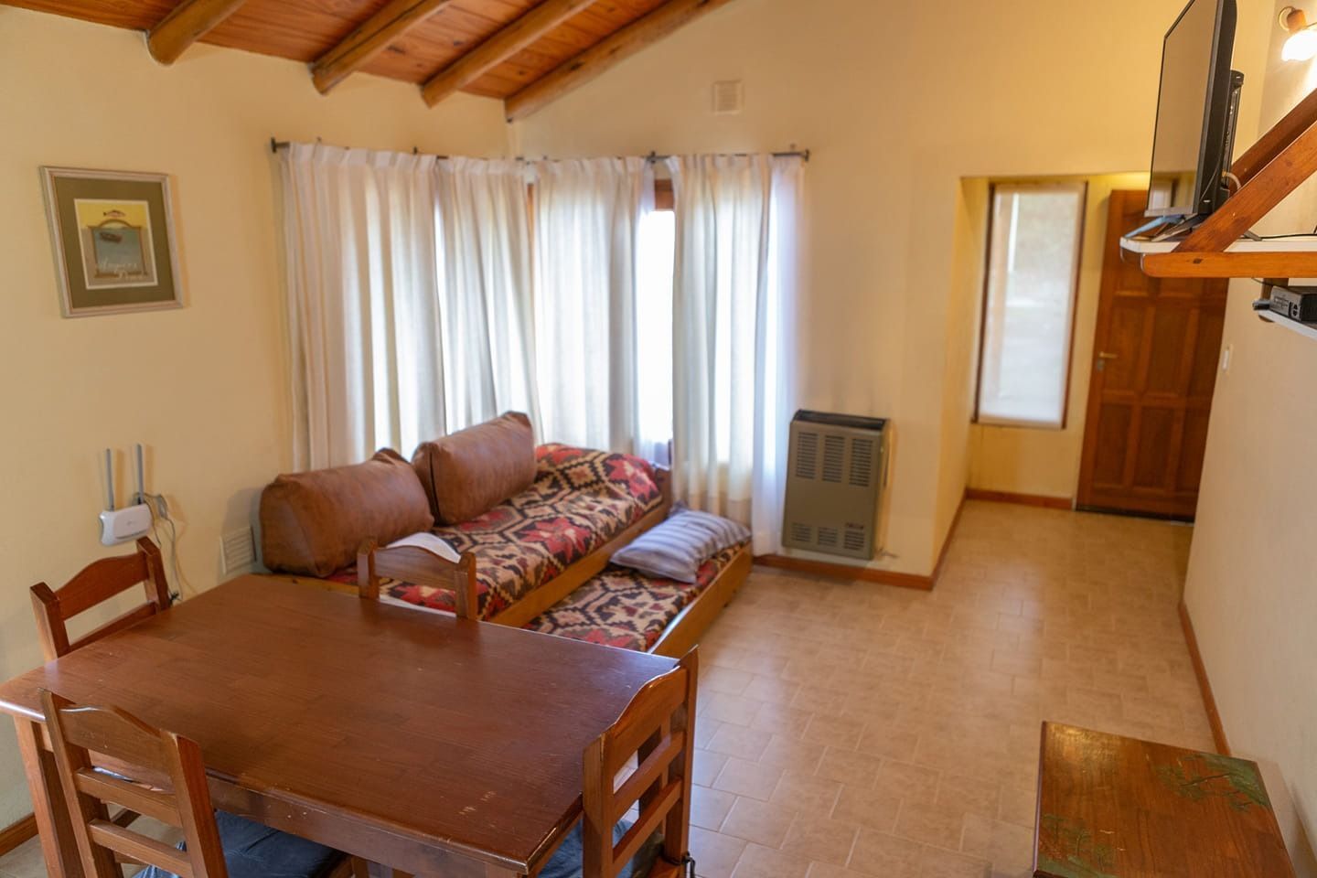 Living room with brown sofa, wooden dining table, and window with curtains.