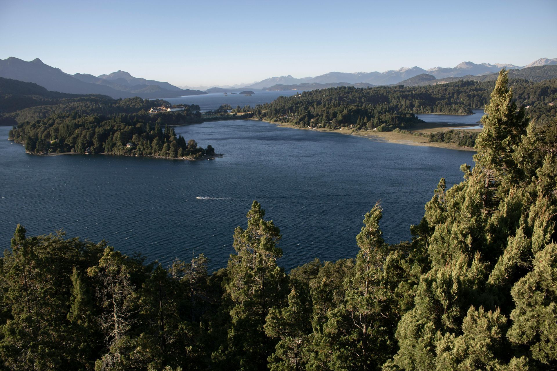 Lake with islands and forested shores under a bright sky.
