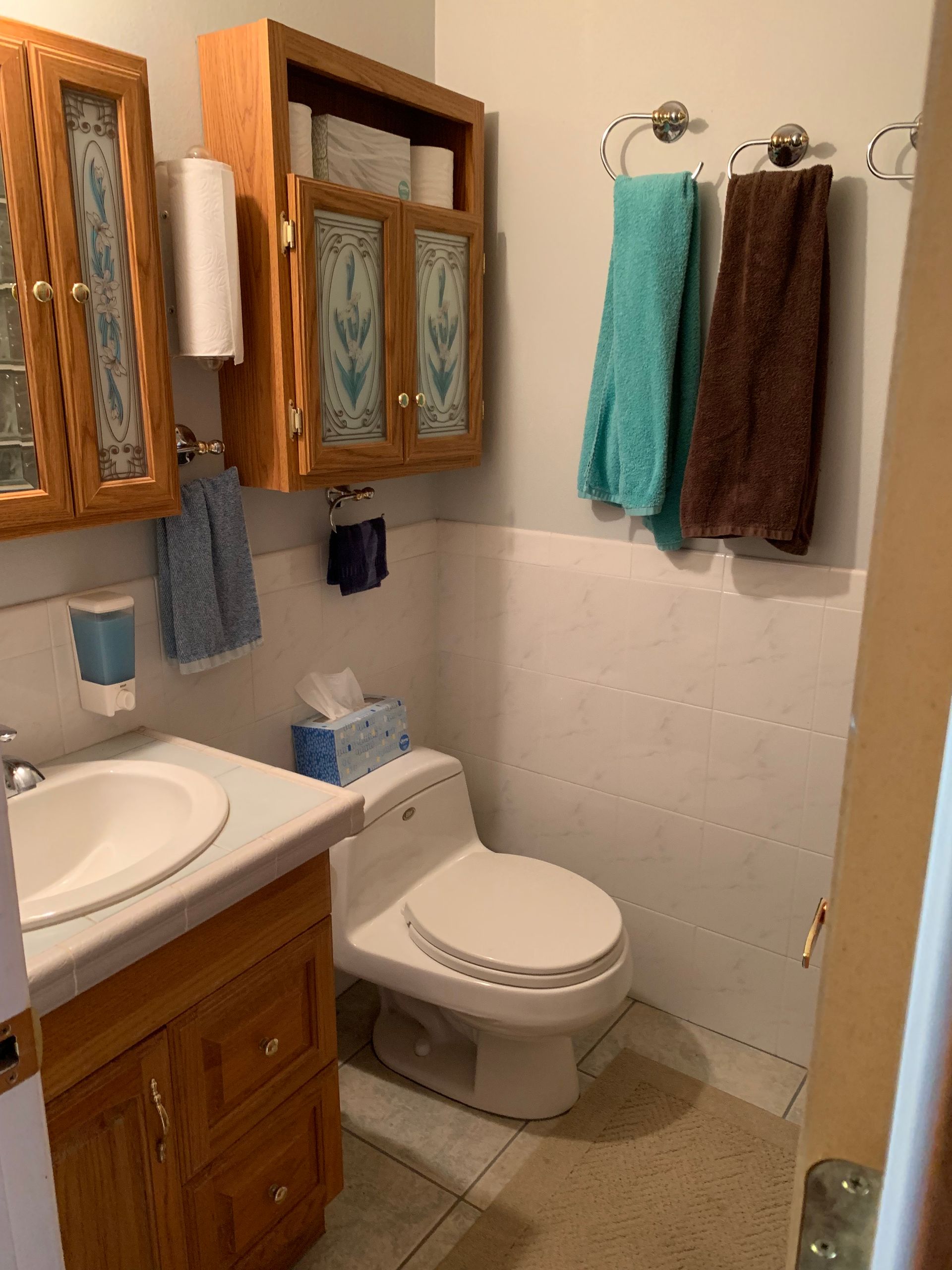 A bathroom with a toilet , sink and cabinets