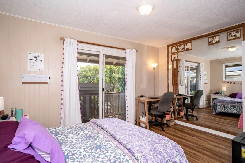 A bedroom with a bed , desk , chair and a large mirror.