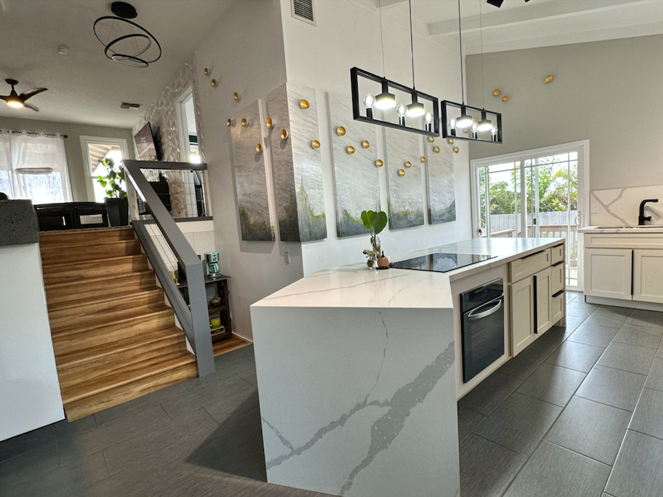 A kitchen with a large island and stairs leading up to the second floor.