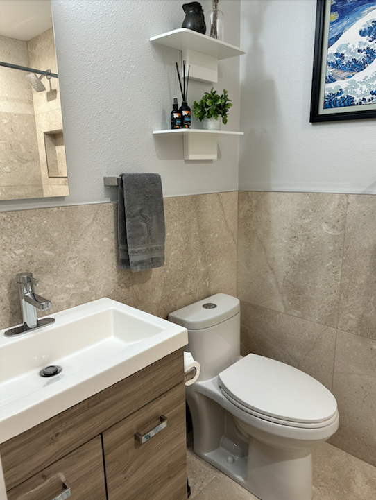 A bathroom with a toilet a sink and a picture on the wall