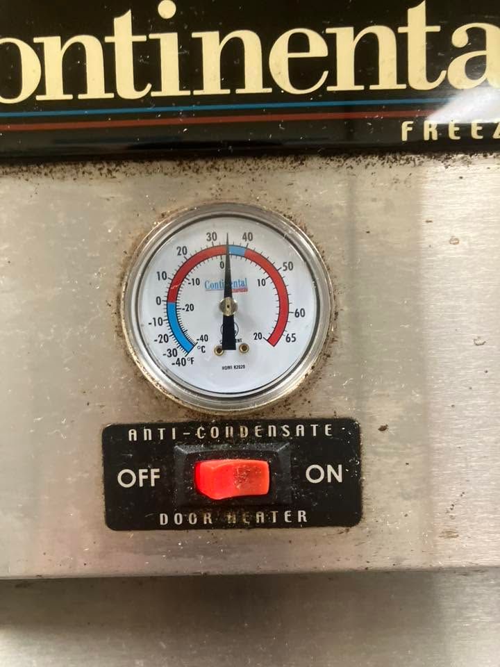 Close-up of a freezer control panel with a temperature gauge and red ON/OFF toggle switch.