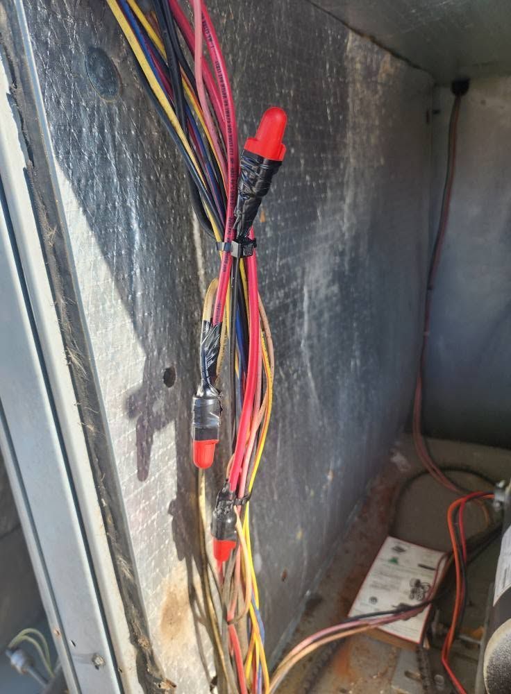 Electrical wires with red connectors running vertically inside a metal cabinet.