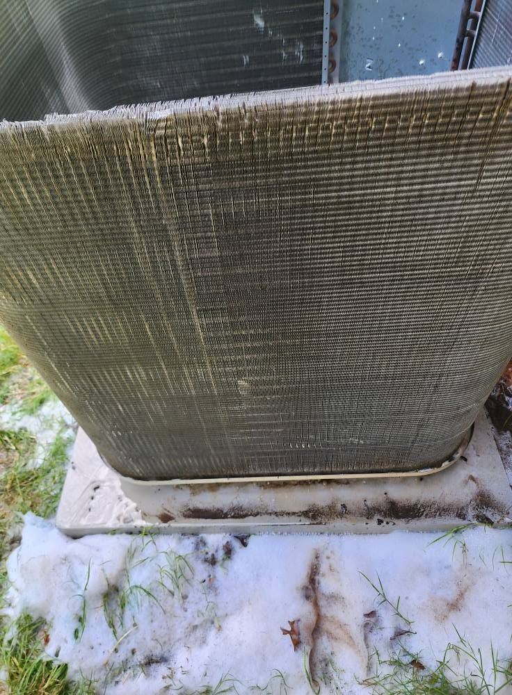 Outdoor air conditioner condenser unit with frost and snow buildup around the base