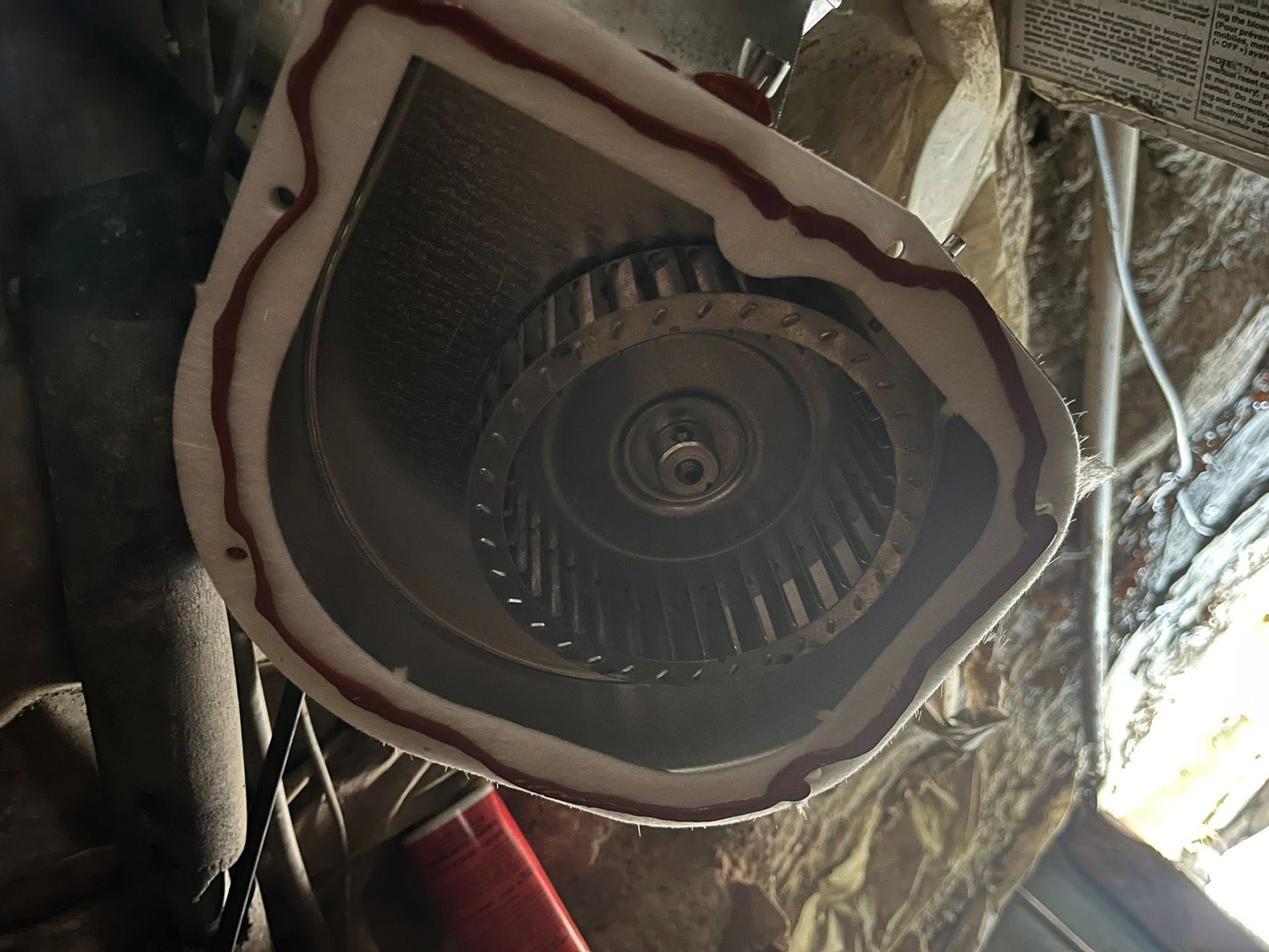 Close-up of a dusty ceiling fan mounted in a rough, unfinished ceiling with exposed wires.