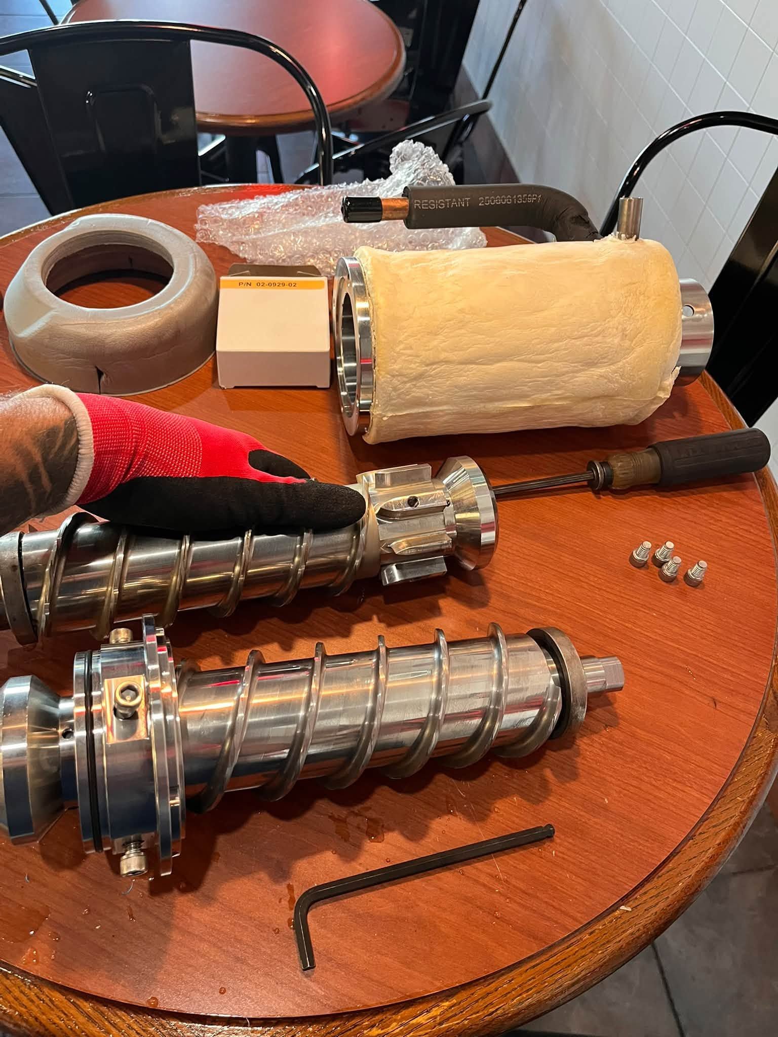 Two metal lamp parts, rolls of tape, and small hardware on a wooden table