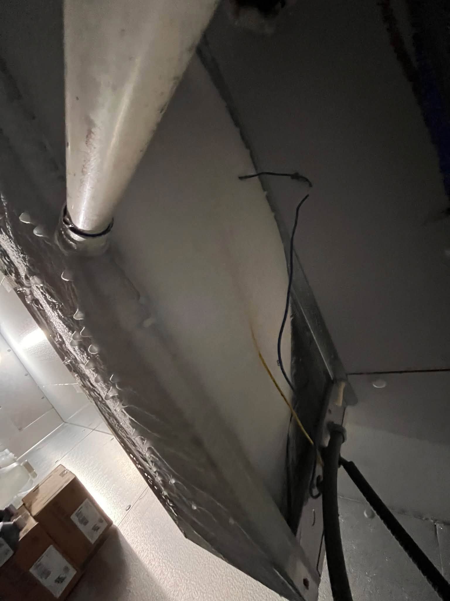 Tilted view of a ducted ceiling vent and exposed wiring in an industrial-looking interior
