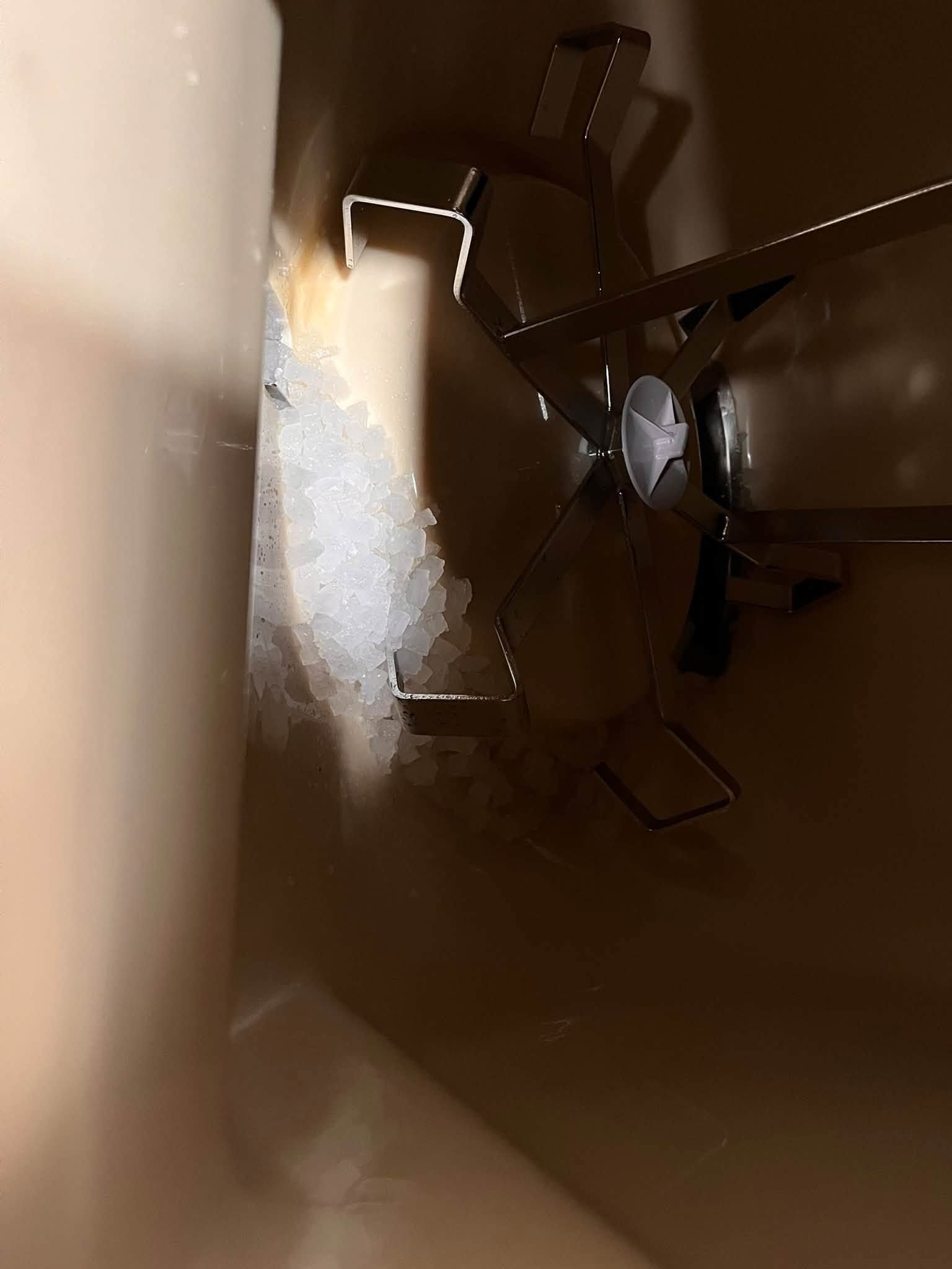 Inside a cardboard box, a small fan sits beside packing foam and a reflective surface.