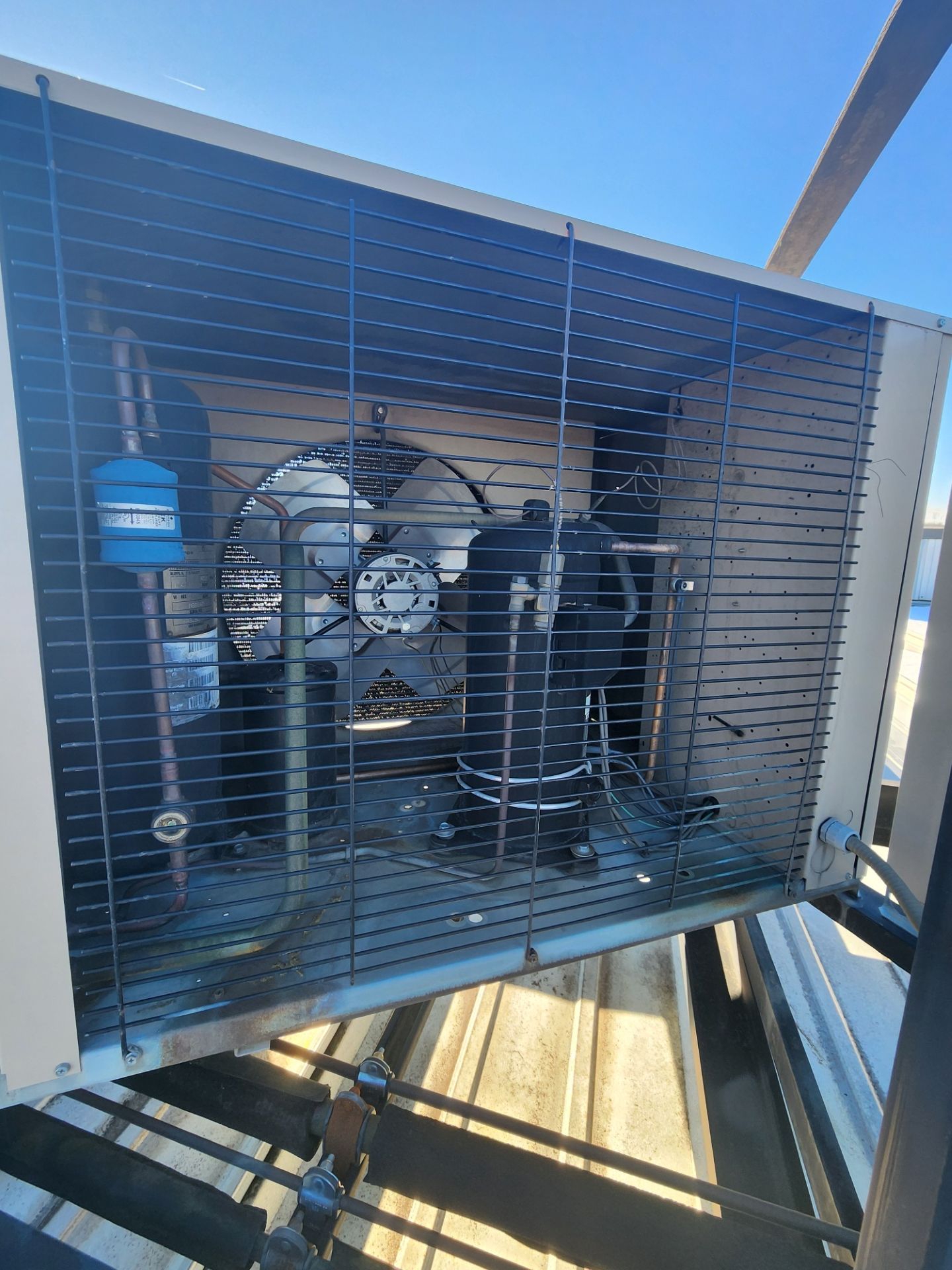 Industrial machine inside a metal enclosure with blue filter and slatted shielding outdoors