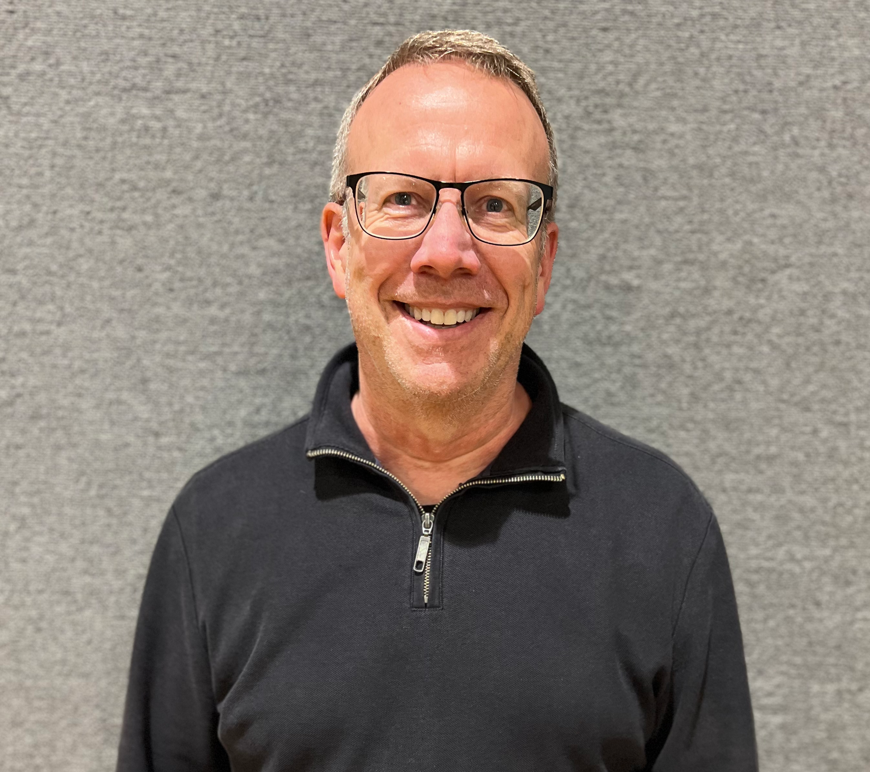a man with a beard and glasses is smiling for the camera .