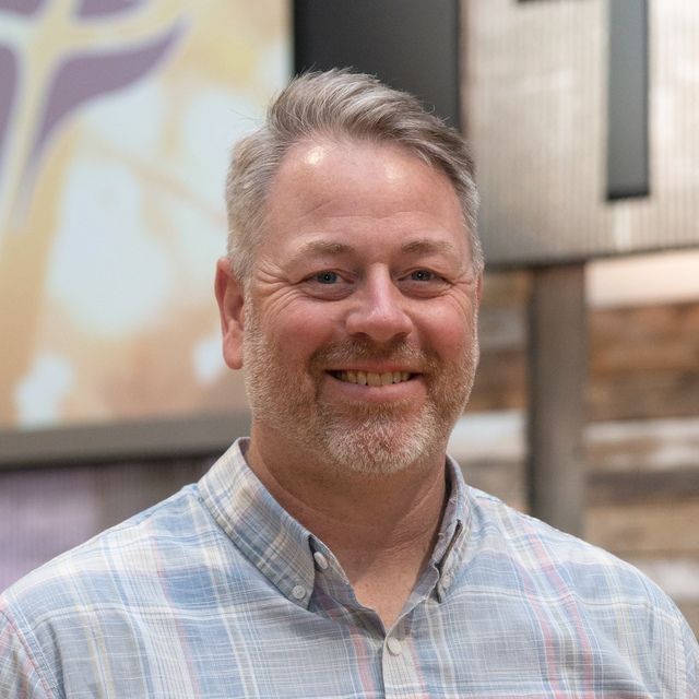 a man with a beard and a plaid shirt is smiling for the camera .