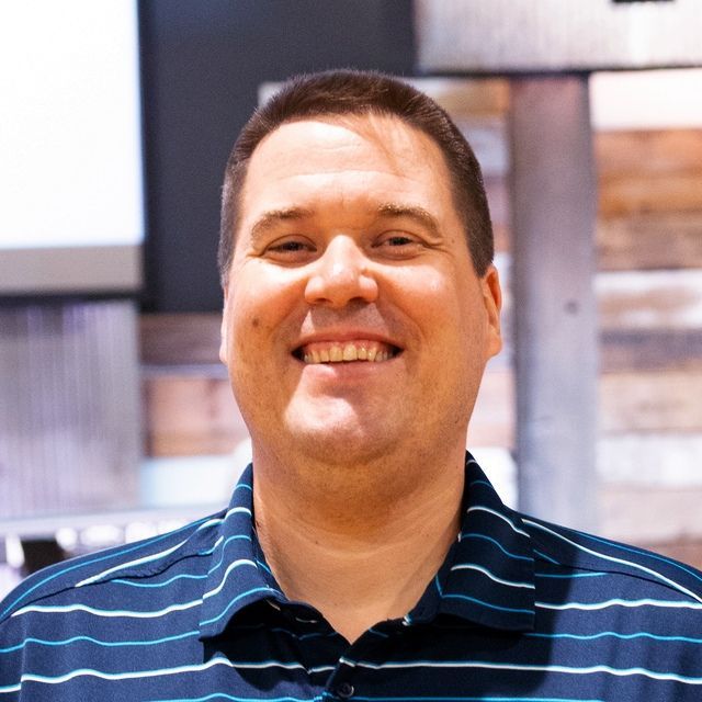 a man wearing a blue and white striped shirt smiles for the camera