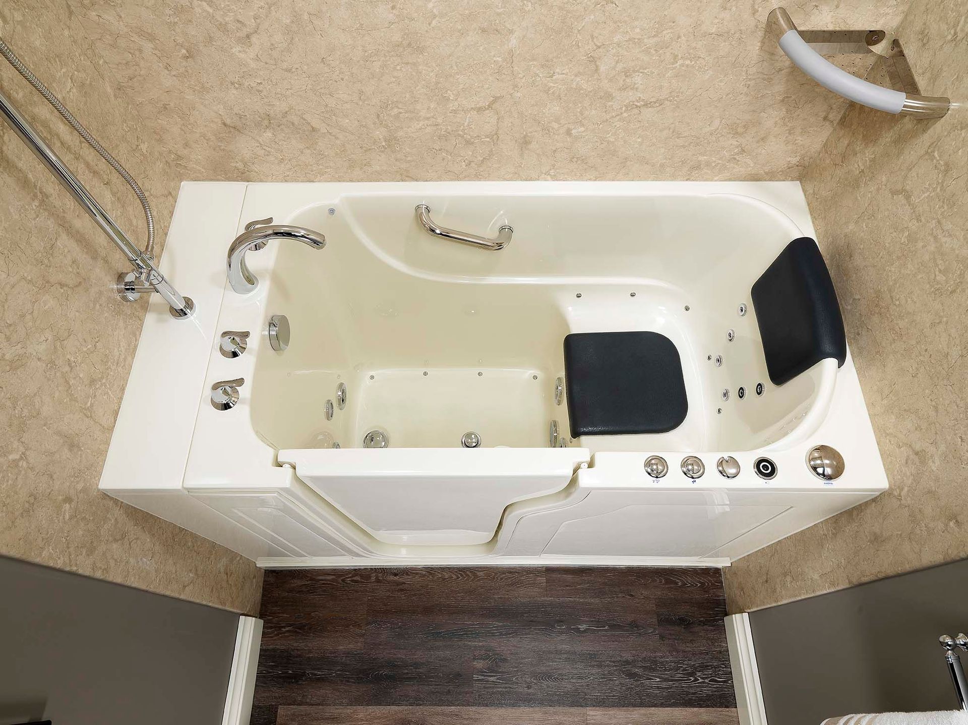 A walk-in white bathtub with silver handles and black seating cushions.