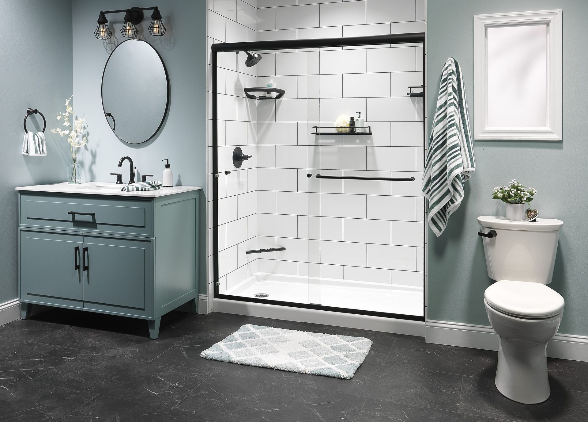 A light blue bathroom with a tiled white shower with black hardware.