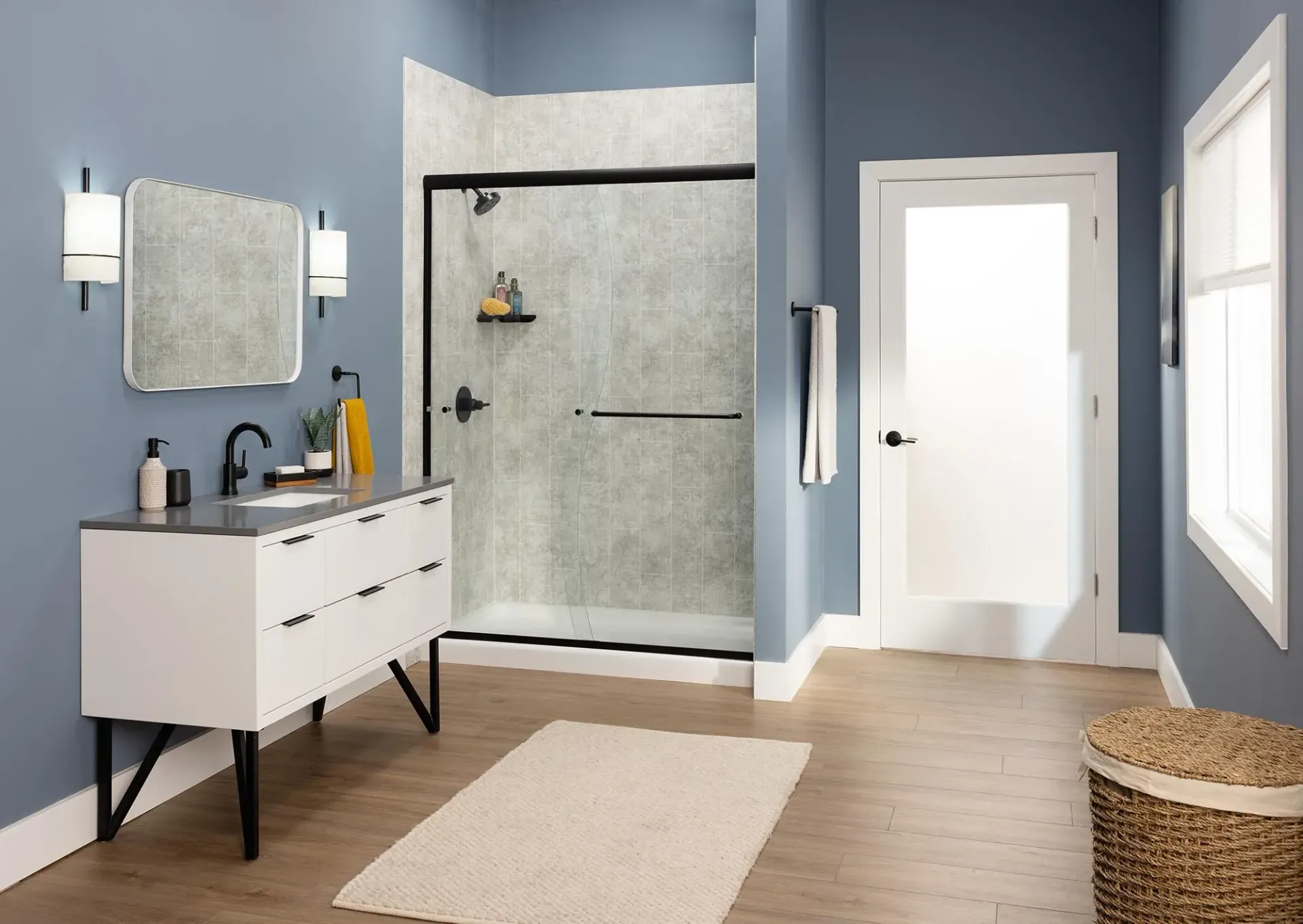 A blue themed bathroom with white and black furniture and a lightly tiled stand up shower.