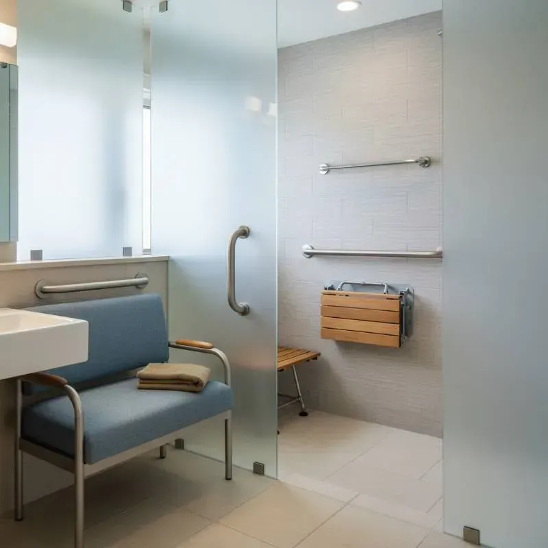 A shower with multiple grab bars and expandable seating.