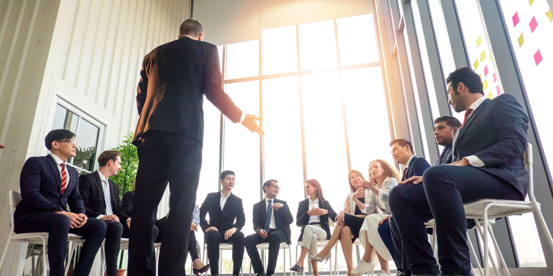 A man is standing in front of a group of business people sitting in chairs.