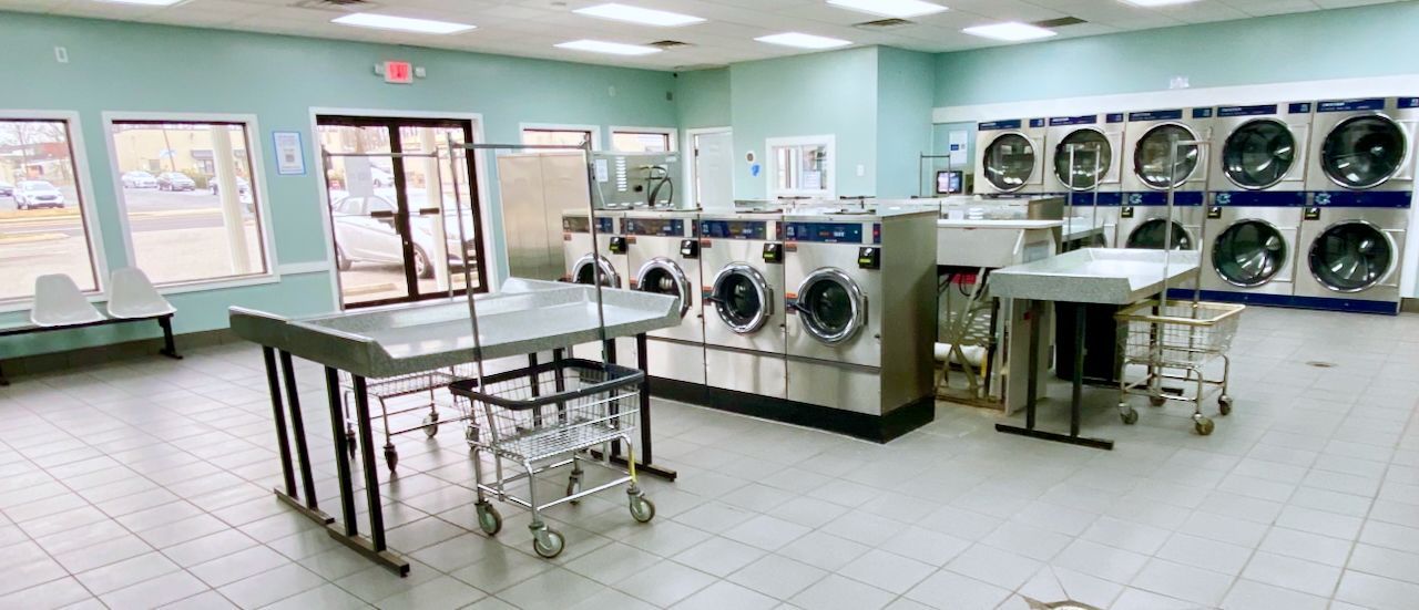 image of clean and spacious laundromat with folding tables and rolling carts