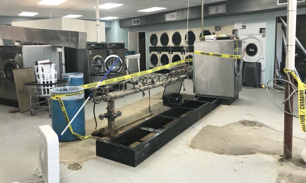 image of laundromat during renovations with caution tape and space for new machines