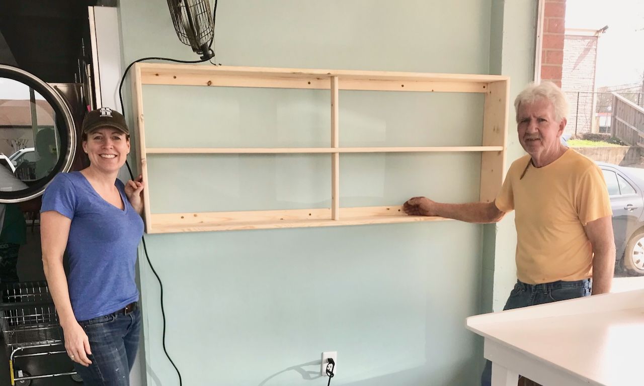 image of man and woman standing beside a wooden bookshelf hanging on a wall