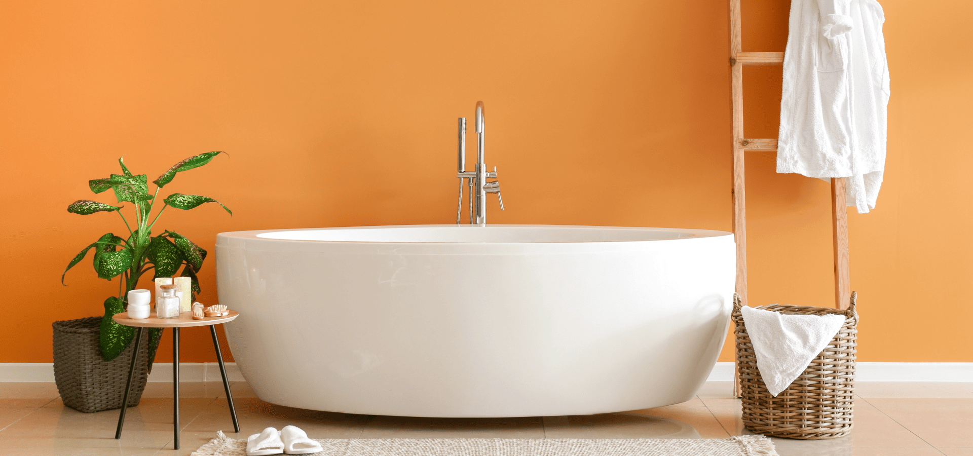 An oval-shaped bathtub in a modern orange-painted bathroom