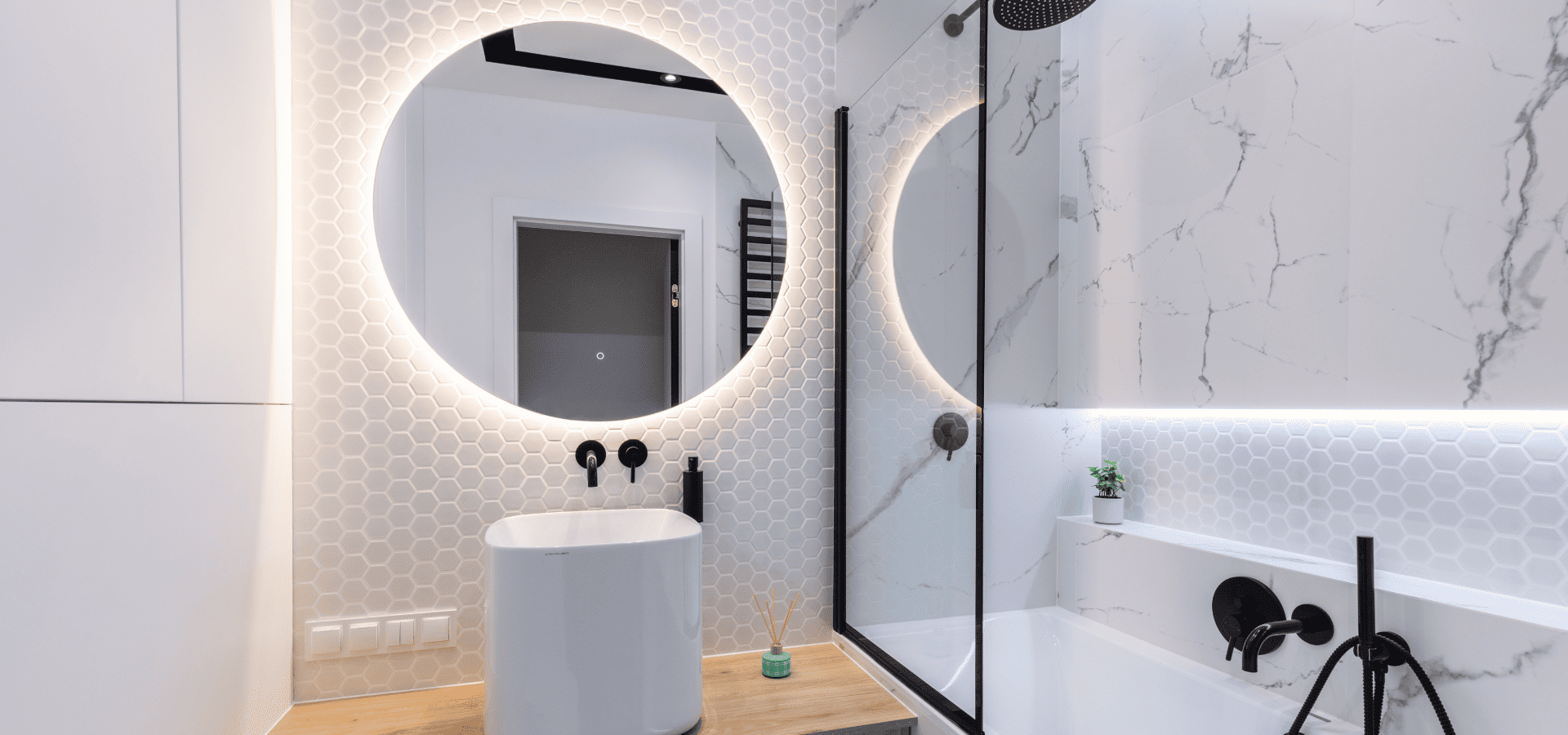 Well-lit contemporary small bathroom with a backlit mirror and accent lighting around bathtub walls