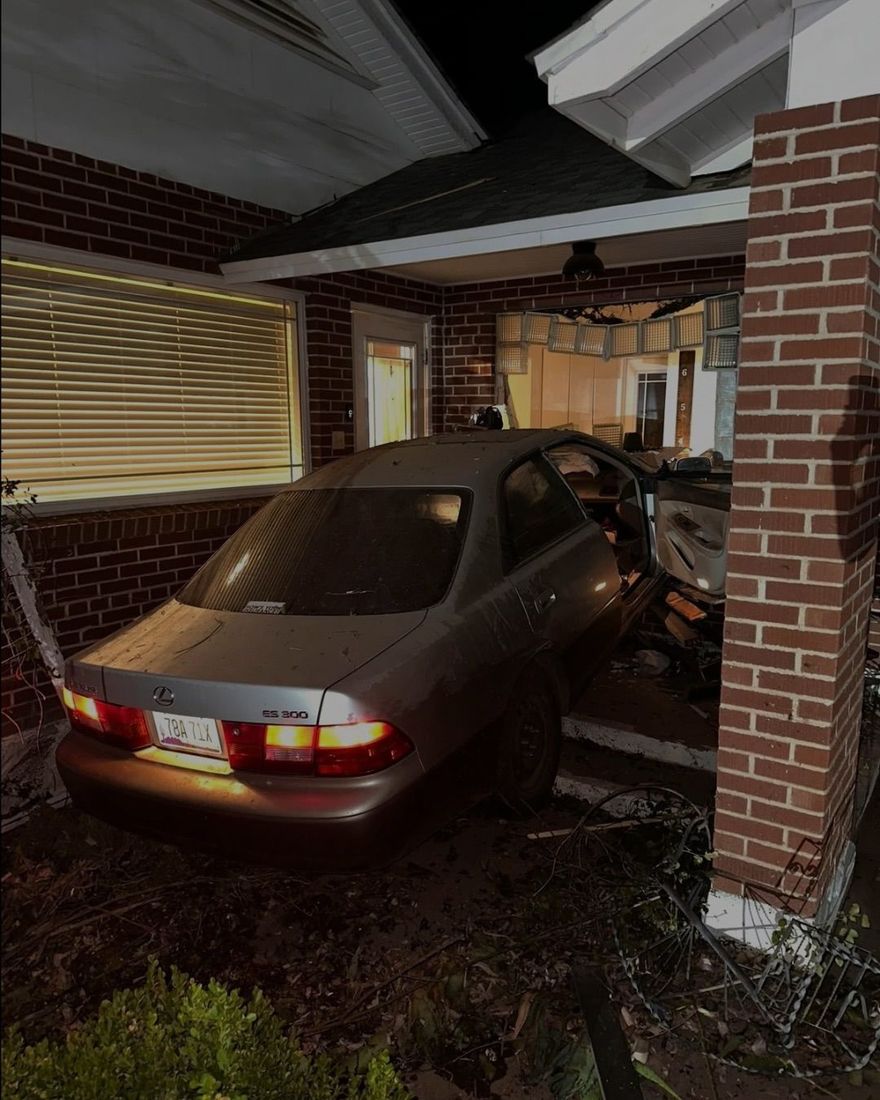Car crashed into a brick porch, wedged under the covered entry of a house.