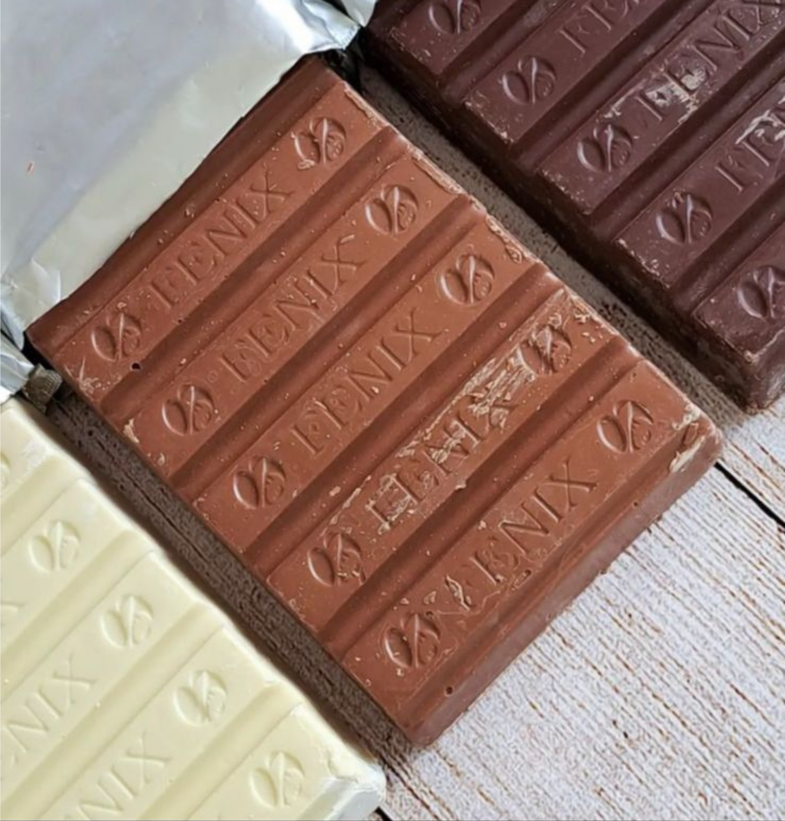 Surtido de tabletas de chocolate blanco, con leche y negro sobre una superficie de madera.