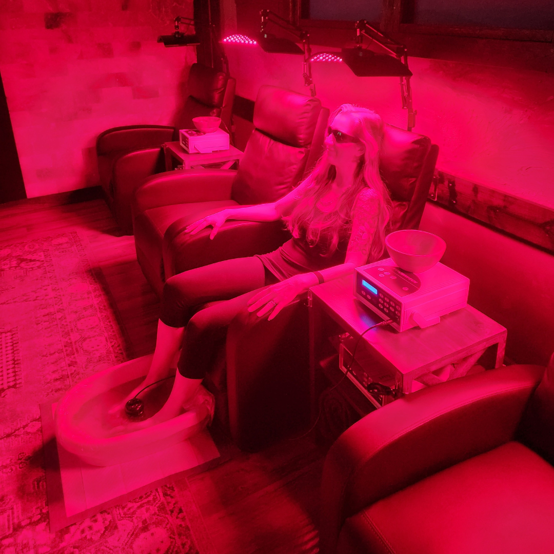 A woman is sitting in a chair under a red light.