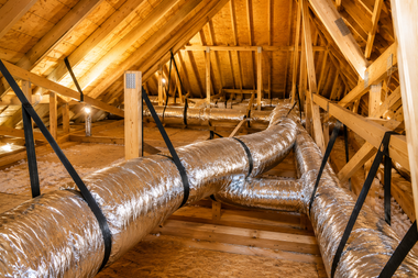 Insulated HVAC ducts running through a wooden attic with exposed beams