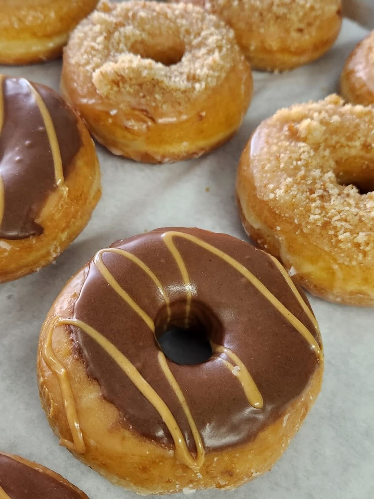 Donuts with chocolate and crumble toppings on a white surface.