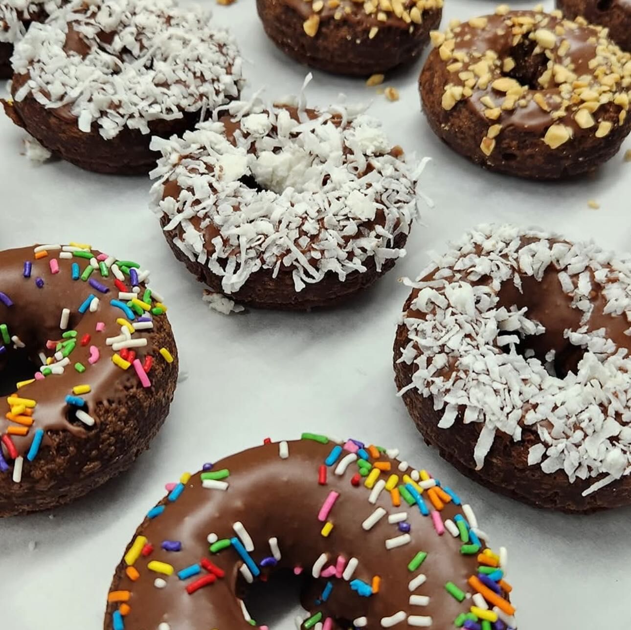Chocolate donuts with various toppings: sprinkles, coconut, and nuts.