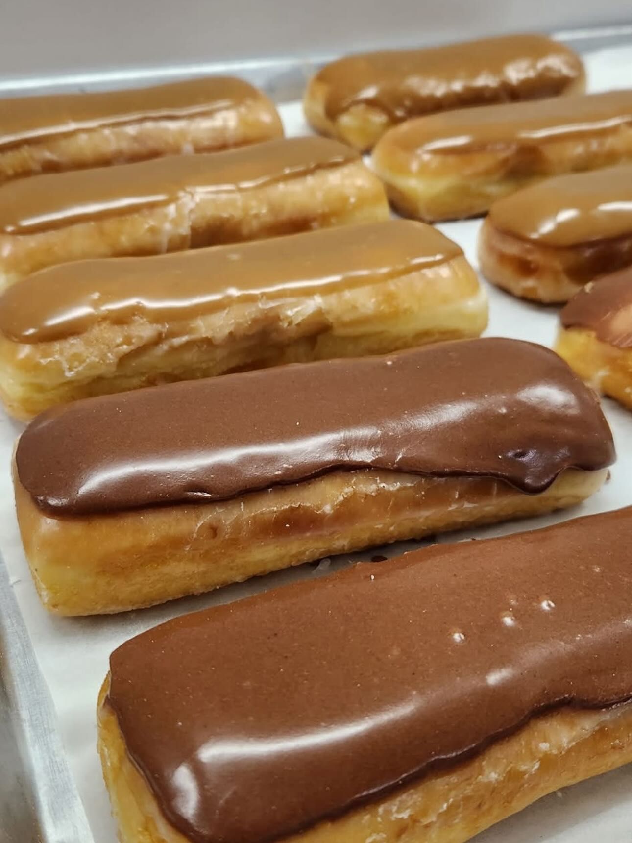 Tray of rectangular glazed donuts, some with chocolate frosting, others with caramel.
