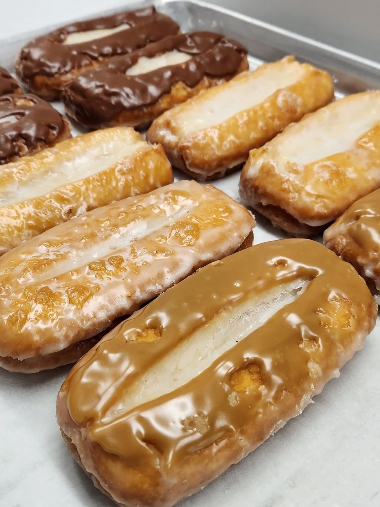 Tray of rectangular donuts with various glazed toppings, light and dark.