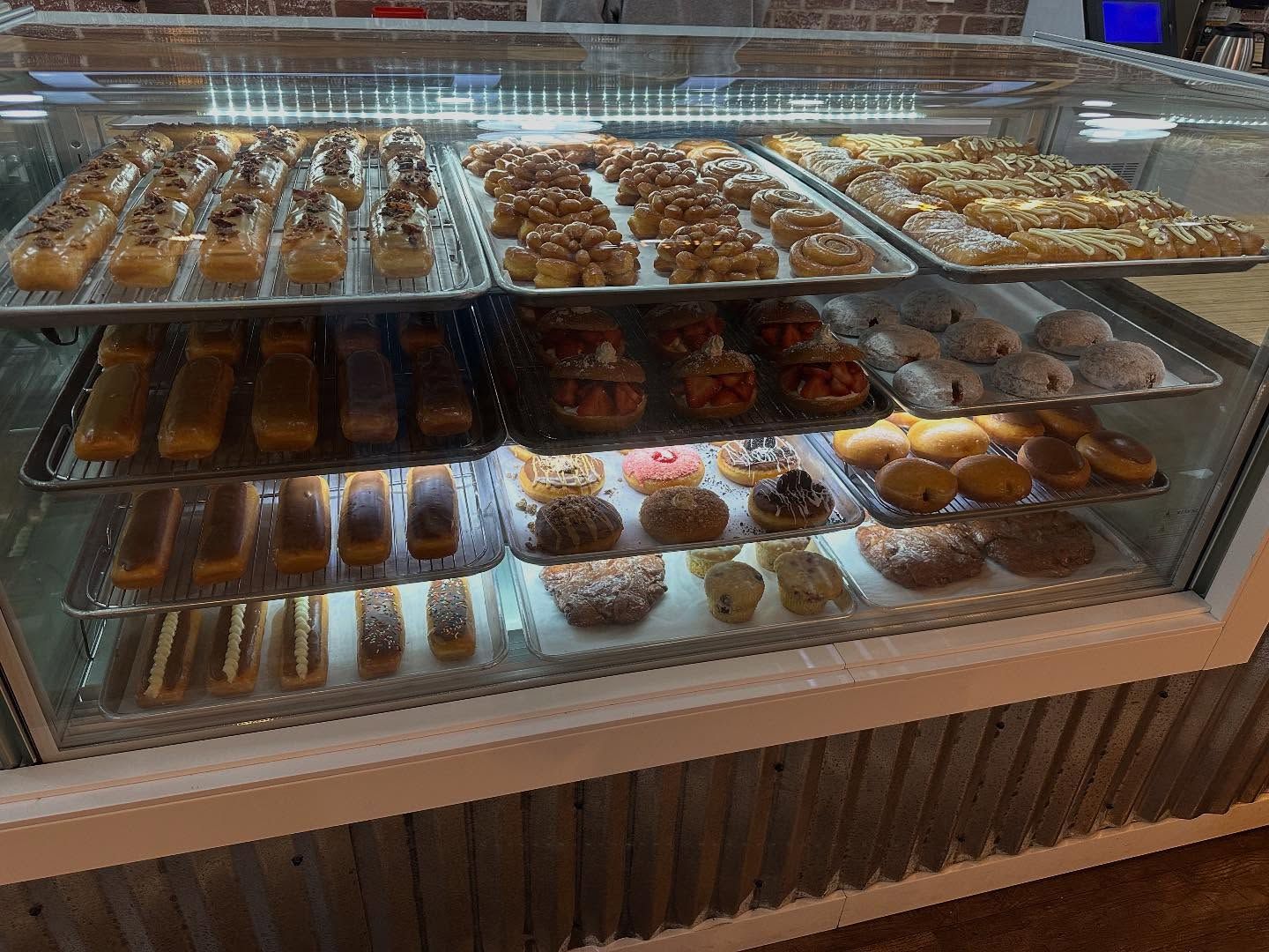 Display case filled with various donuts: glazed, frosted, and filled.