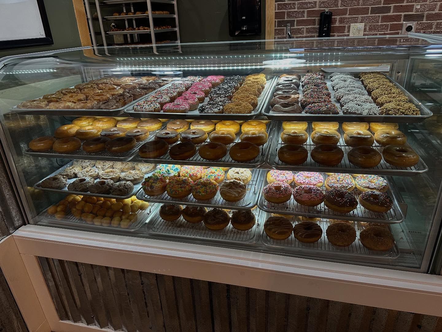 Display case filled with various donuts in a bakery.