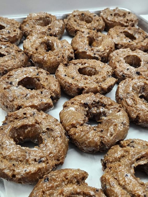 Tray of glazed, round chocolate doughnuts.
