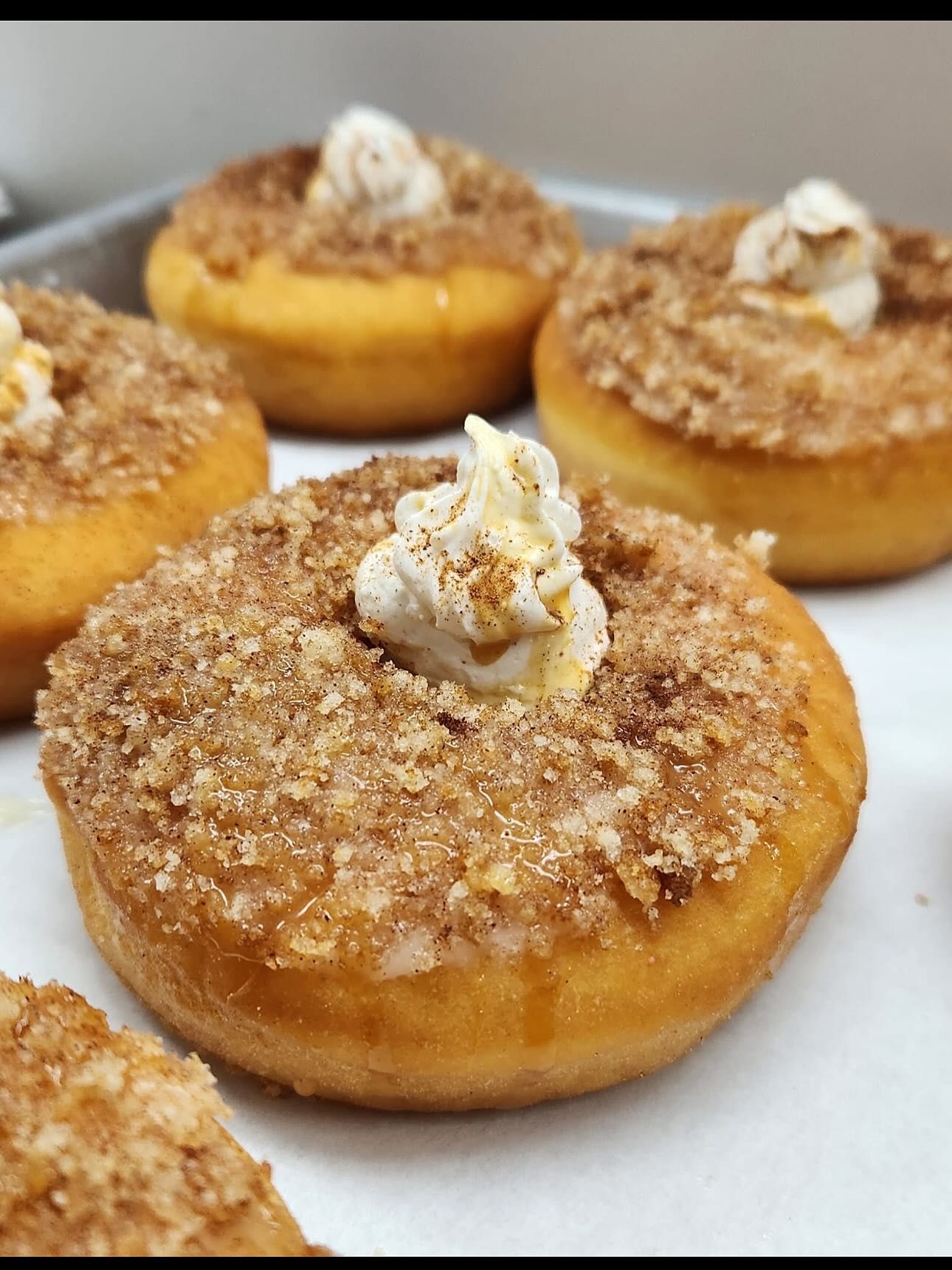 Close-up of frosted donuts with a crumble topping and whipped cream.