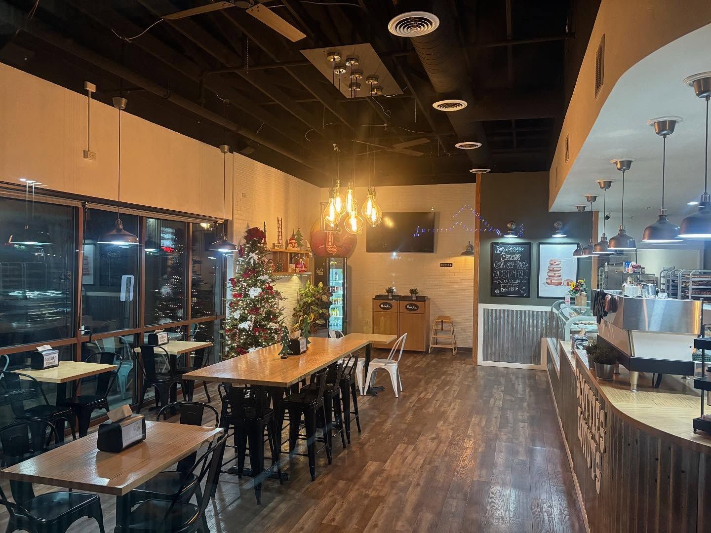 Interior of a cafe with tables, chairs, Christmas tree, counter, lights, and windows.