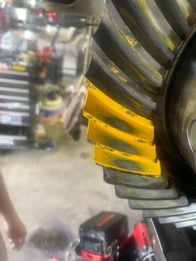 Close-up of yellow and gray metal gears in a workshop, with blurred machinery in the background. | Phase 2 Automotive